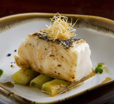 Grilled cod fillet on braised leeks, garnished with crispy shallots.