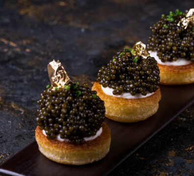 pancakes with black caviar and gold leaf on a background of old wooden surfaces