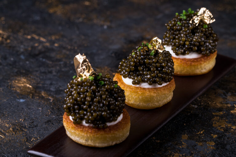 pancakes with black caviar and gold leaf on a background of old wooden surfaces