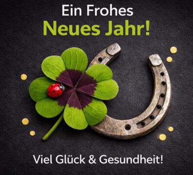 Ein Hufeisen und ein Kleeblatt auf schwarzem Grund mit Neujahrsgrußtext
