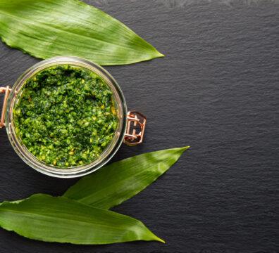 Homemade pesto sauce made with Allium ursinum leaves, known as wild garlic, ramsons, buckrams, broad-leaved garlic, wood garlic, bear leek or bear's garlic. Lot of copy space on black stone texture.