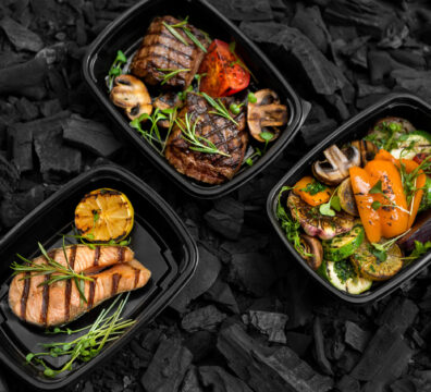 Freshly cooked Grilled menu for take away in black boxes on coal background