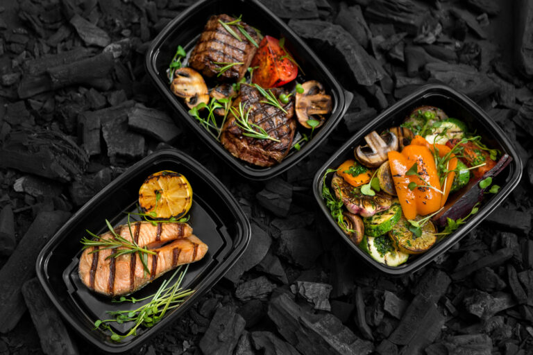 Freshly cooked Grilled menu for take away in black boxes on coal background